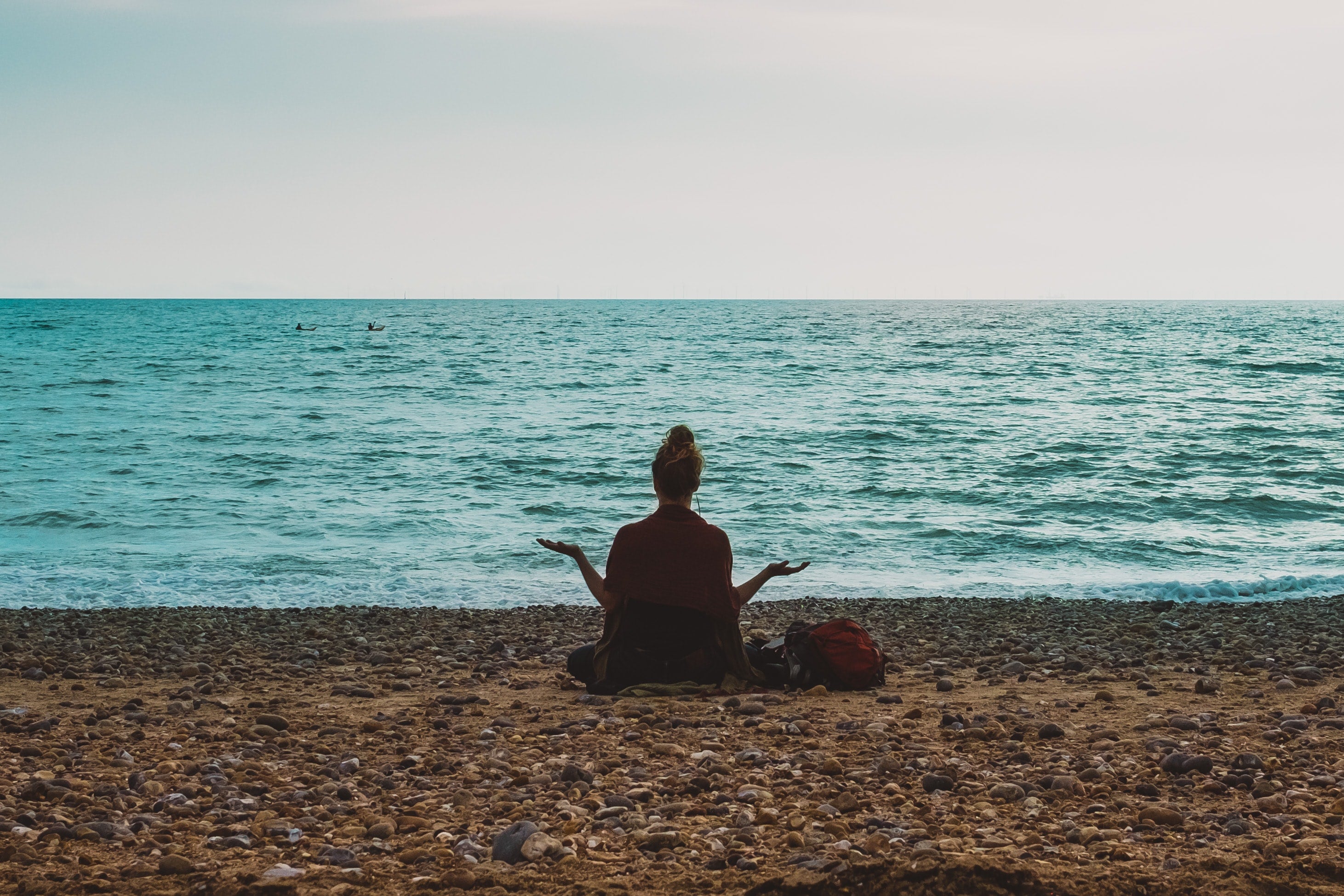 Woman sitting in yoga pose on beach looking at the ocean